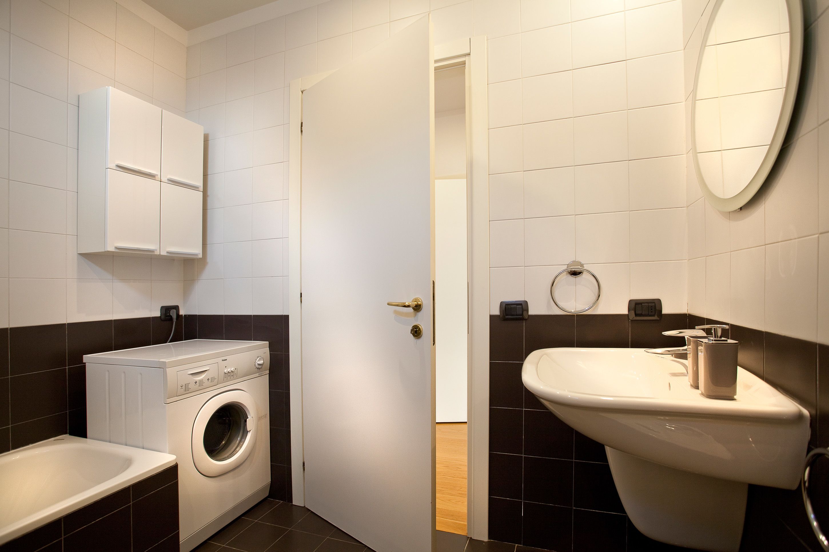 A compact bathroom with a washing machine, a sink, and a toilet.