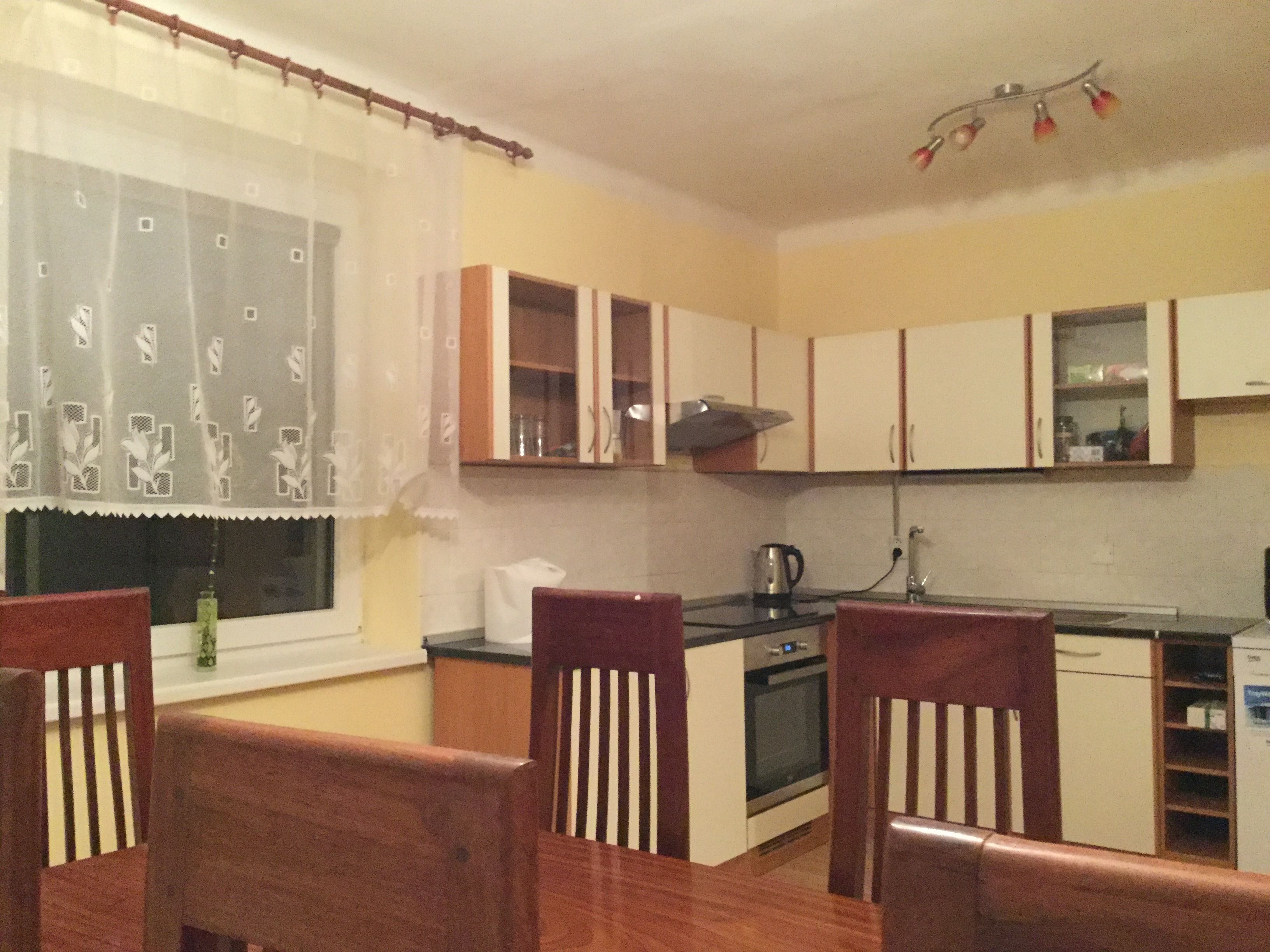 Cocina compacta con armarios de madera, estufa y mesa de comedor con sillas.