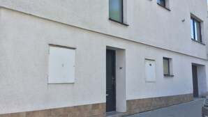 Fachada de edificio con varias ventanas, puertas y suelo de baldosas.