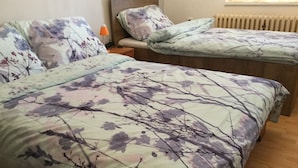 Un dormitorio con dos camas, cada una con ropa de cama de diseño floral. Entre las camas, un mesita de noche con una lámpara.