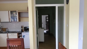 Una cocina con microondas, tostadora y armarios. Se ve una silla de madera en primer plano.