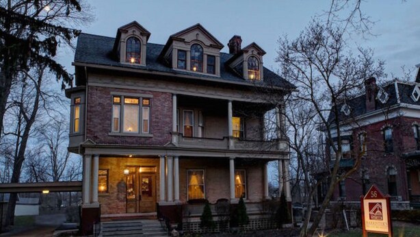 A two-story brick house with a porch, multiple windows, and a well-lit entrance. - Barrister's Bed & Breakfast (Seneca Falls)