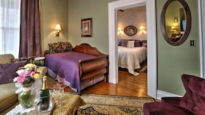 A room with a bed, a sofa, a table with a vase of flowers, and a mirror on the wall. - Barrister's Bed & Breakfast (Seneca Falls)