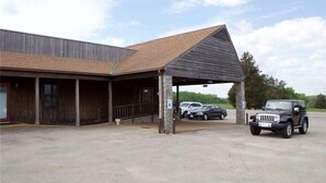 A building with a covered entrance, a parking area, and a black vehicle parked in front. - Sheldon's Motel by OYO Keysville Near Hwy 360 (Keysville)
