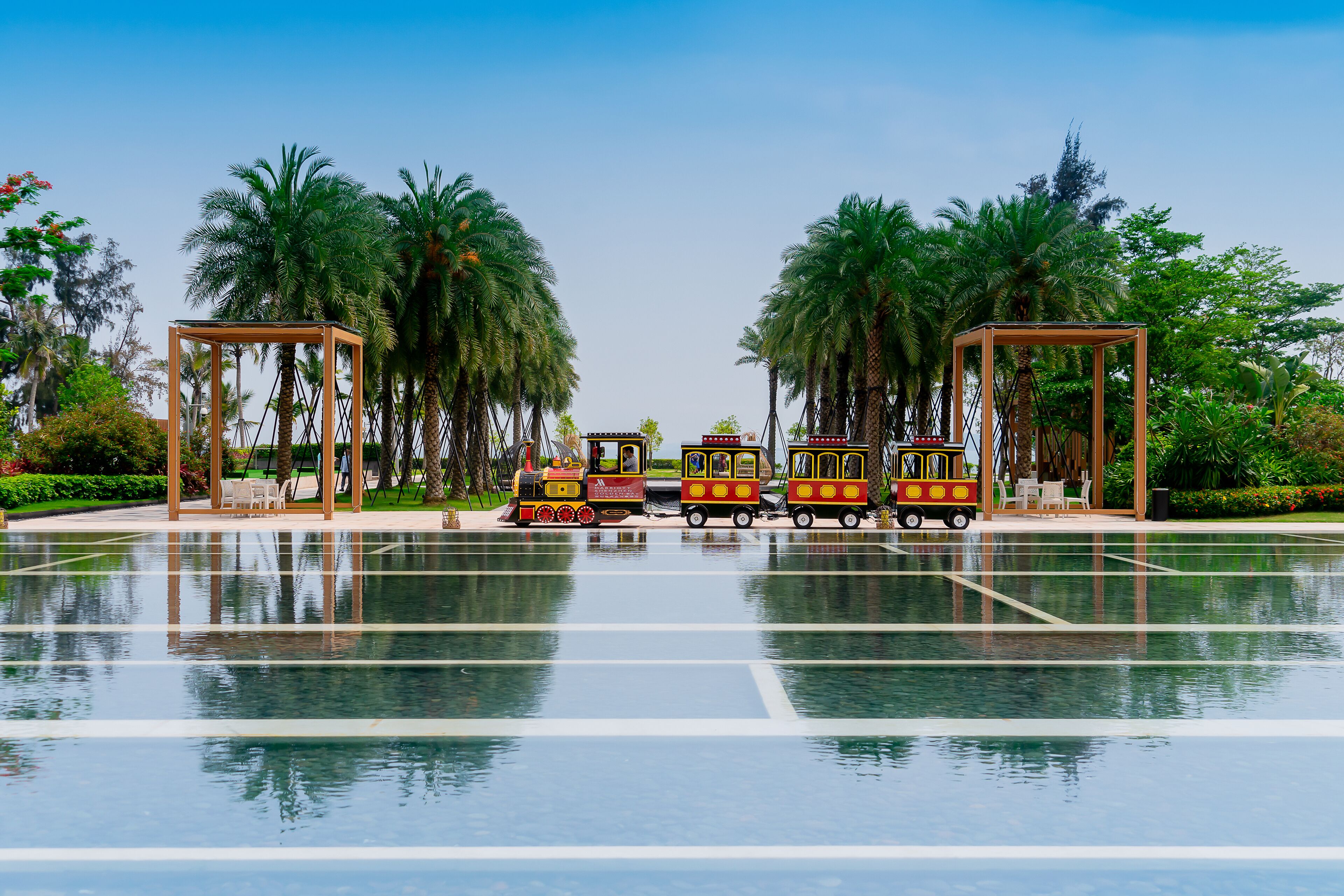 A water park with a train ride, palm trees, and a clear sky.
