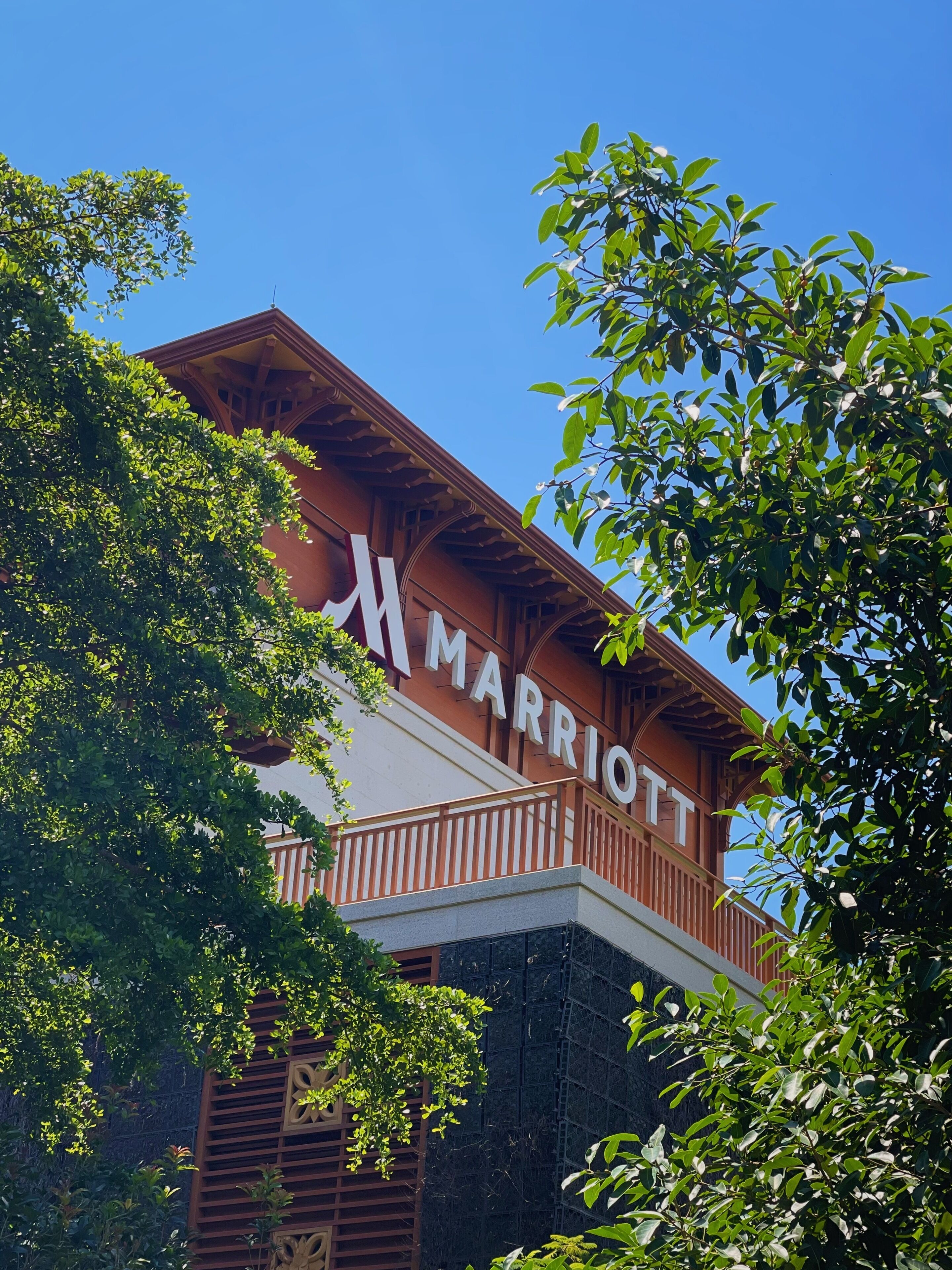 A Marriott hotel with a prominent sign, surrounded by lush green trees.