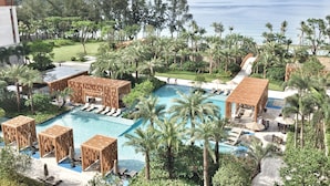 Et resort med en stor swimmingpool, loungeområder og palmer.