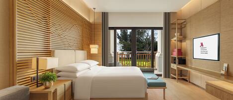 Habitación de hotel moderna con una cama grande, mesitas de noche, televisión y balcón con vista a árboles.