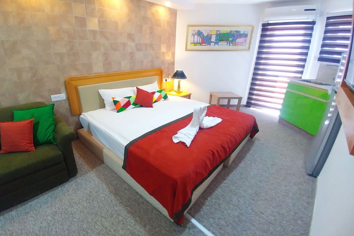 Una habitación de hotel con una cama, un sofá verde, una mesita y un armario verde.
