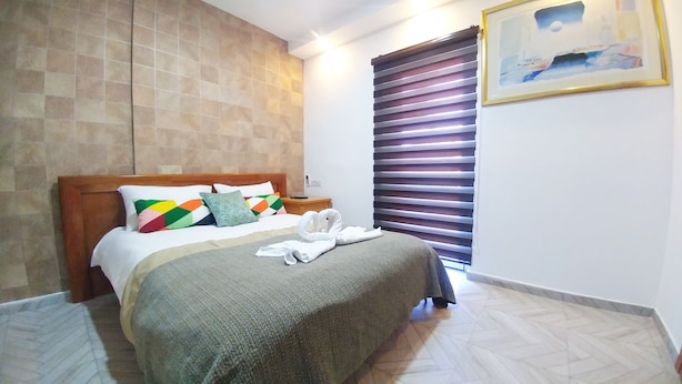 Una cama bien hecha con almohadas coloridas, un cabecero de madera y una colcha.