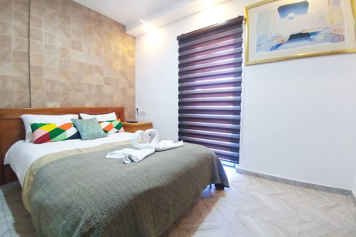 Una cama bien hecha con almohadas coloridas, un cabecero de madera y una colcha.