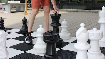 Een man speelt schaak op een groot bord buiten.
