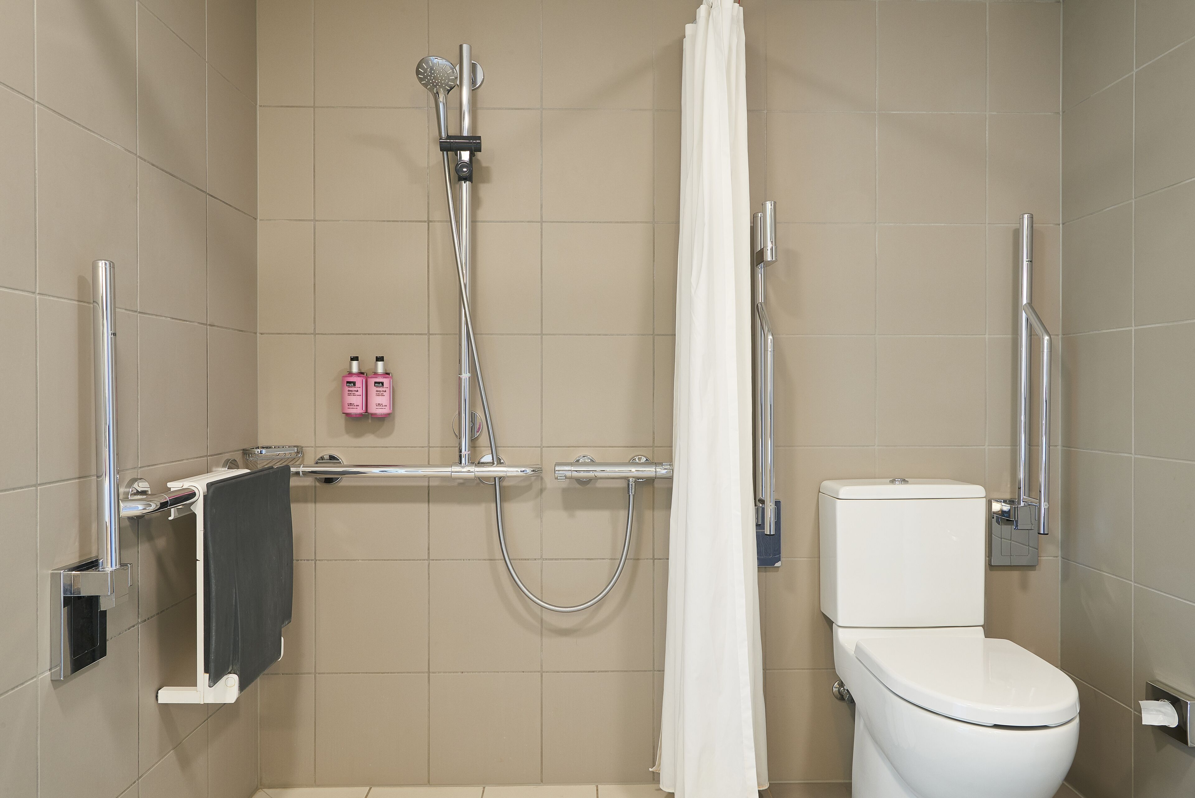 A modern bathroom with a shower, toilet, and towel rack.
