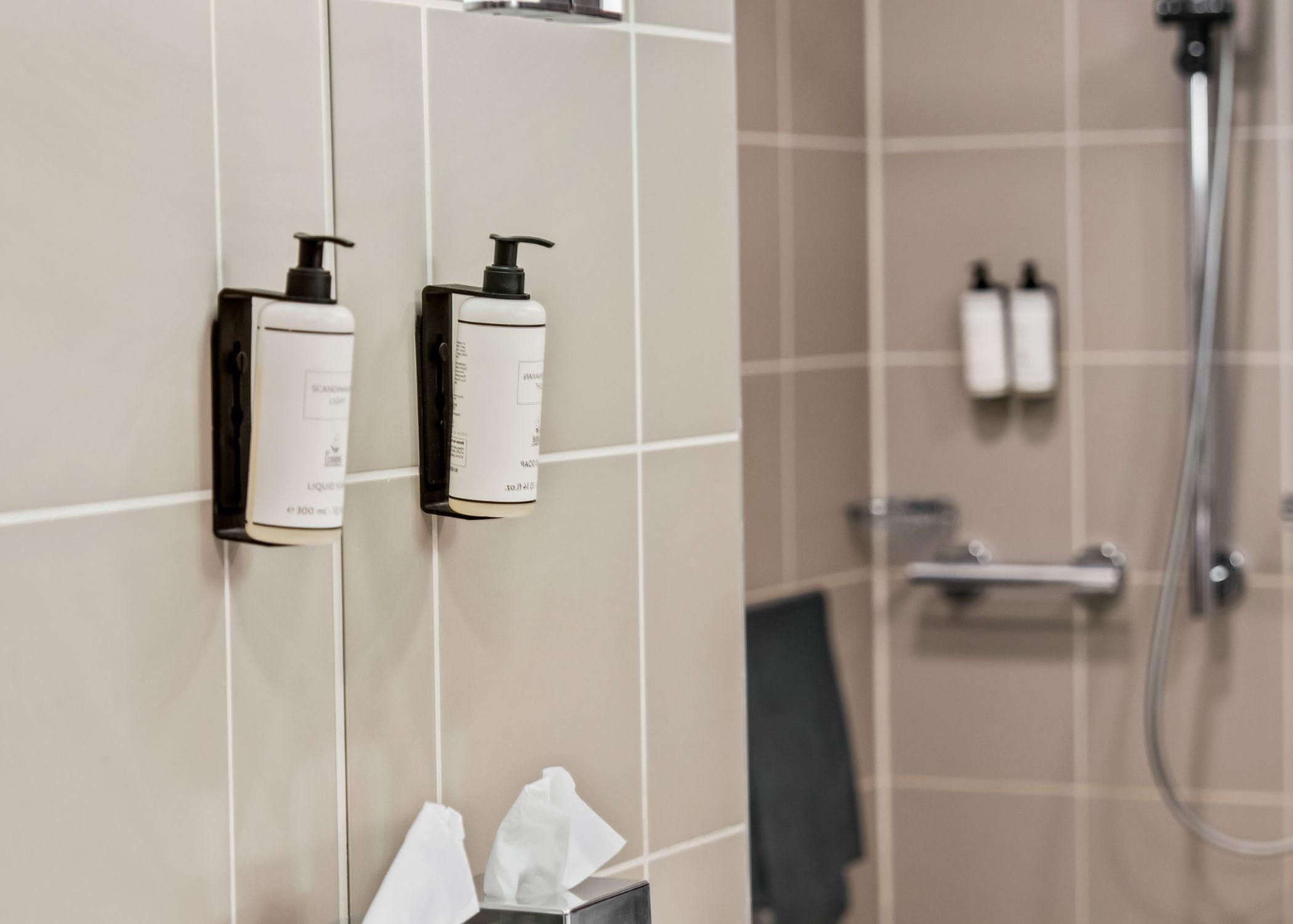A bathroom with a hand dryer and a towel dispenser mounted on the wall.