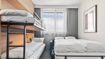 Habitación de hotel con literas, una cama individual, un escritorio y una ventana con cortinas.