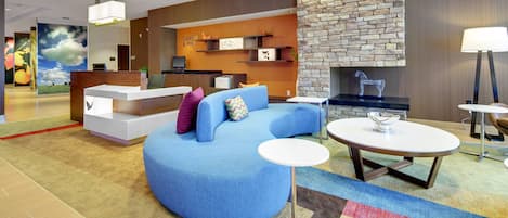 Un moderno vestíbulo de hotel con una recepción, zona de estar y chimenea de piedra.
