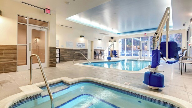 An indoor swimming pool with clear water, a lifeguard chair, and a warning sign. - Fairfield Inn & Suites by Marriott Asheville Tunnel Road (Asheville)