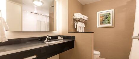 A modern bathroom with a black vanity, a large mirror, a toilet, and a shower curtain.