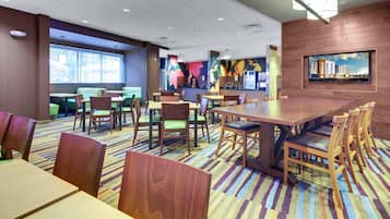 A modern hotel lobby with multiple seating areas, including a large dining table and several booths.