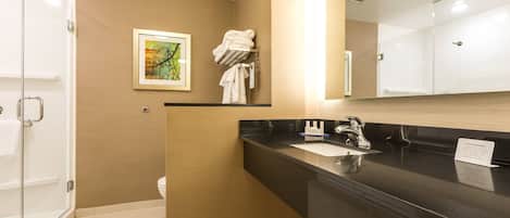 Une salle de bain moderne avec un plan de toilette noir, un lavabo et un miroir. On y trouve un porte-serviettes avec des serviettes et un tableau encadré accroché au mur.