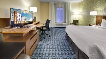 Une chambre d’hôtel équipée d’un lit, d’un bureau, d’une chaise, d’une télévision et d’une fenêtre avec des rideaux.
