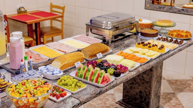 Une table de buffet proposant une variété d’aliments, notamment des fruits, des pâtisseries et des desserts.