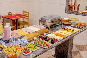 Une table de buffet proposant une variété d’aliments, notamment des fruits, des pâtisseries et des desserts.
