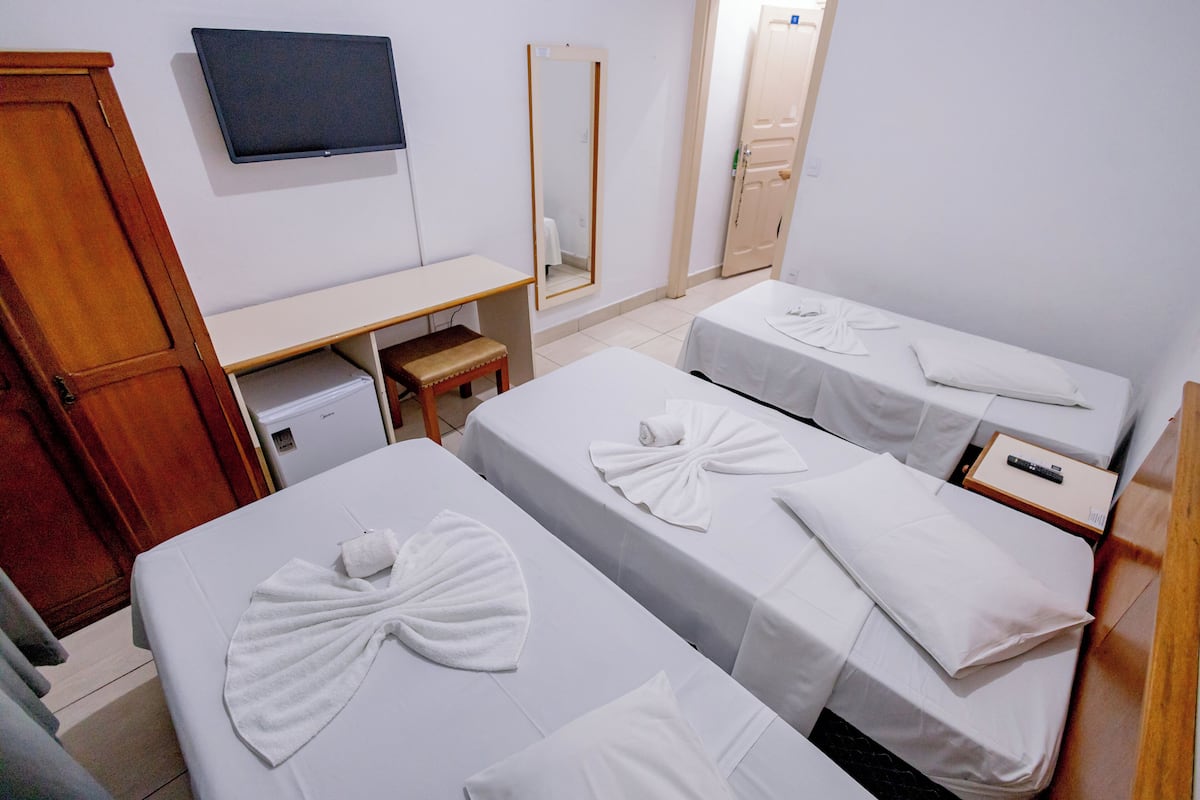 Una habitación de hotel con dos camas, un escritorio, un televisor y un espejo.