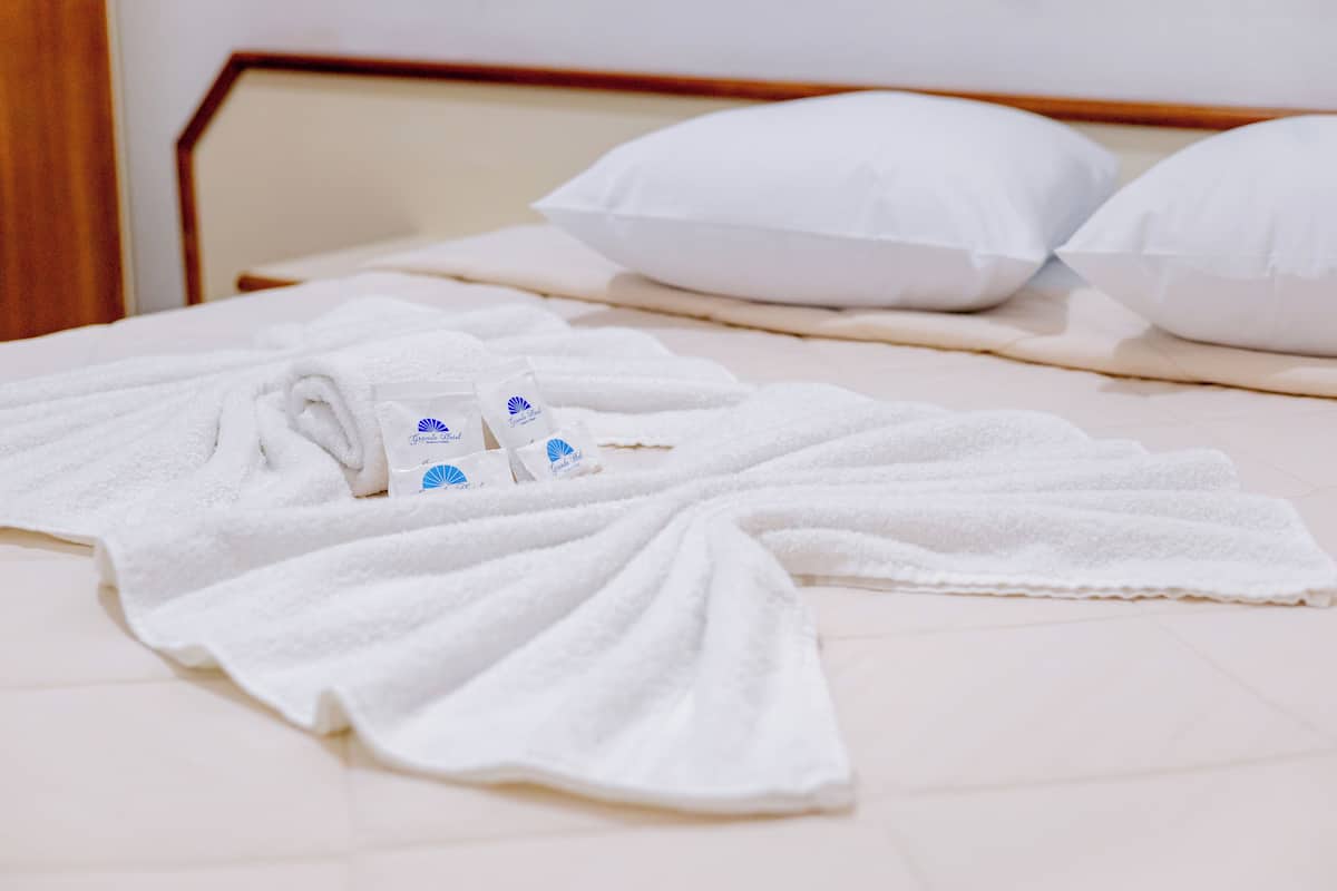 Una cama bien hecha con toallas blancas y un frasco de loción.