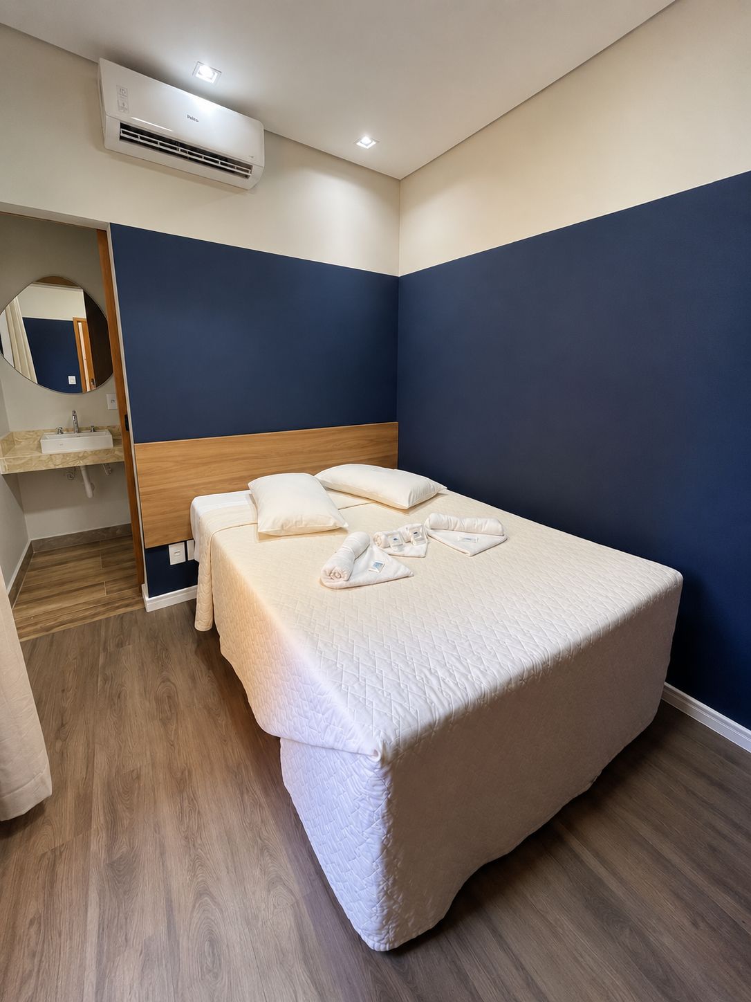 A single bed with a wooden headboard, a bedside table, and a mirror.