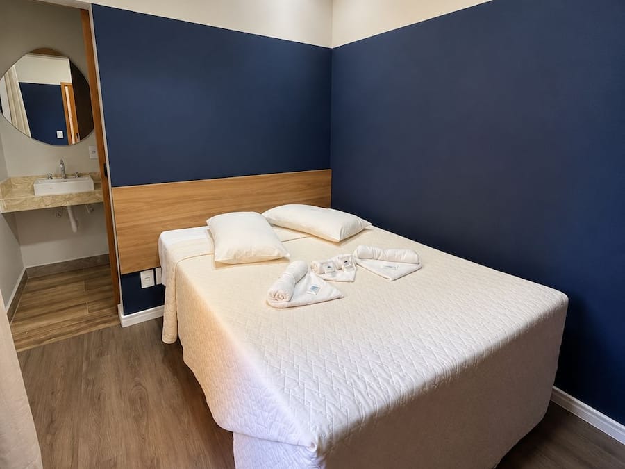 A single bed with a wooden headboard, a bedside table, and a mirror.