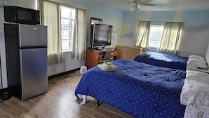 A bedroom with two beds, a television, a refrigerator, and a ceiling fan. - Mountaineer Motel (Mount Storm)