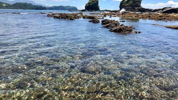 Una vista despejada de una costa rocosa con agua tranquila y montañas a lo lejos.