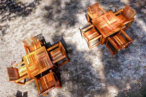 Un conjunto de comedor exterior de madera con mesa y sillas dispuestas sobre una superficie de concreto.
