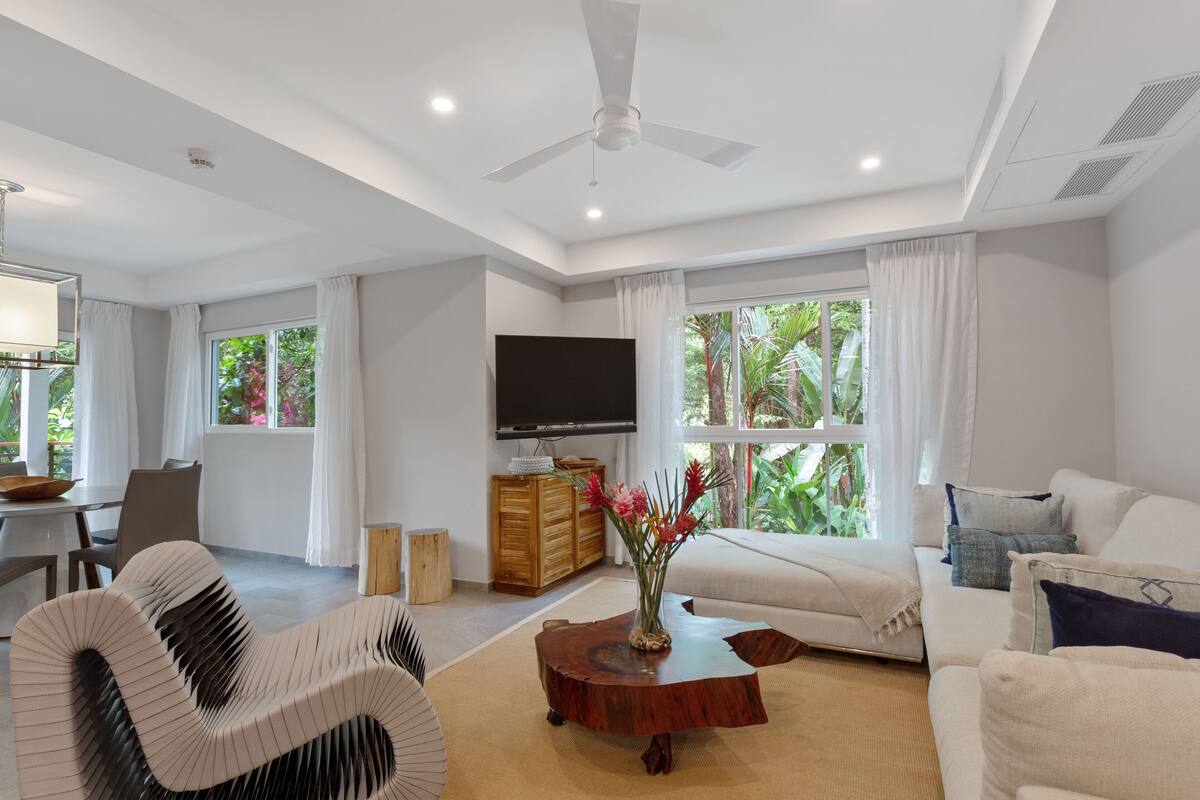 A modern living room with a sofa, a curved chair, a coffee table, and a TV.