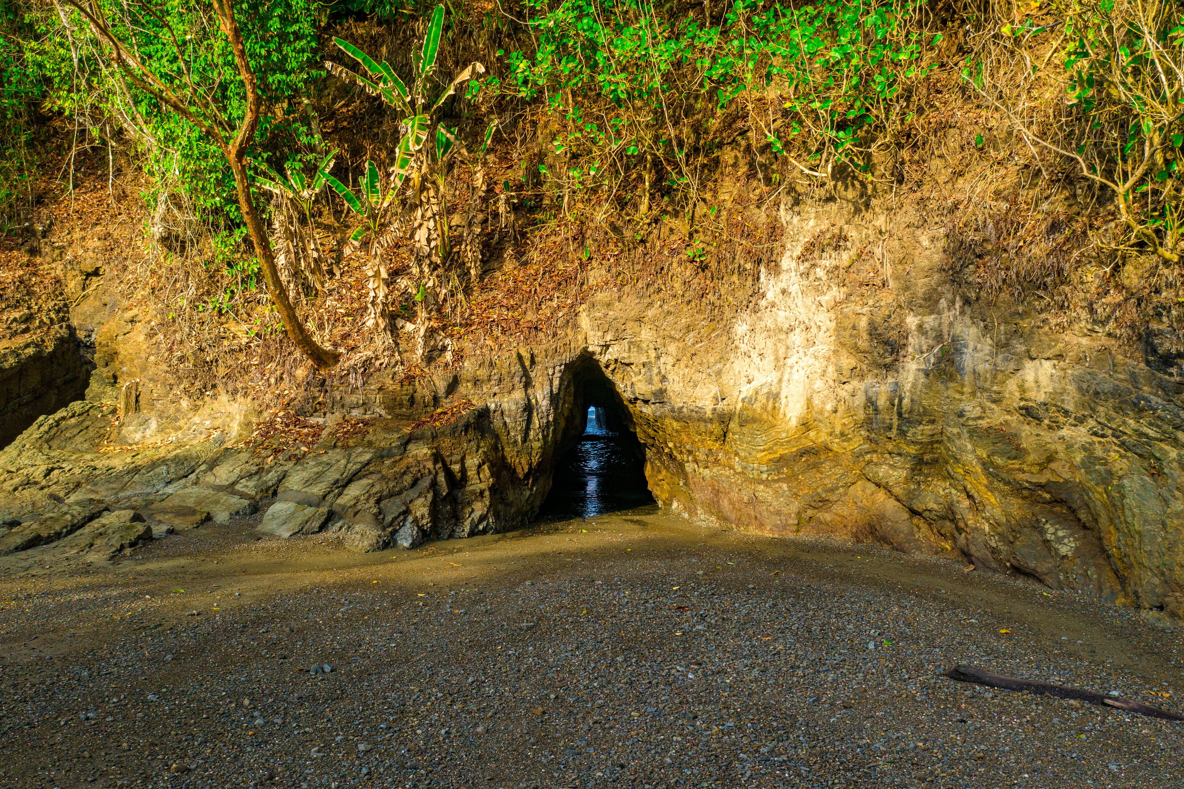 A natural cave entrance with a narrow passage leading into a darker area.