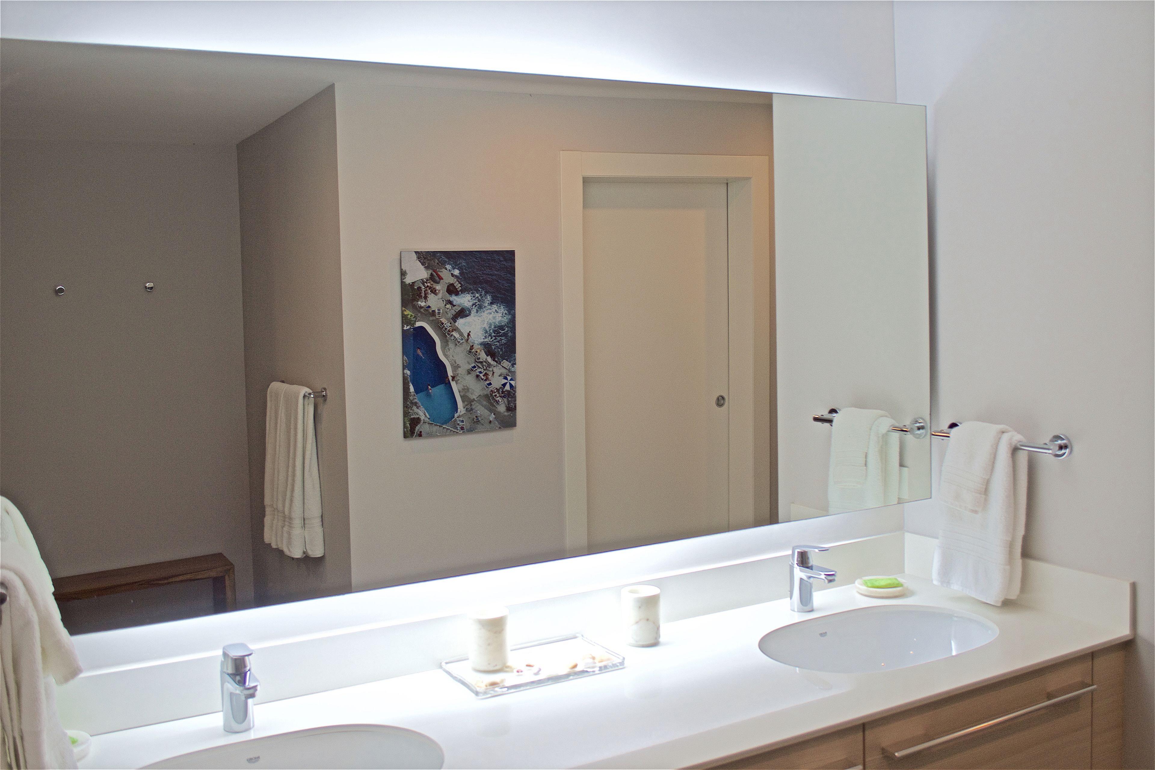 Une salle de bain moderne avec un grand miroir, deux lavabos et un banc.