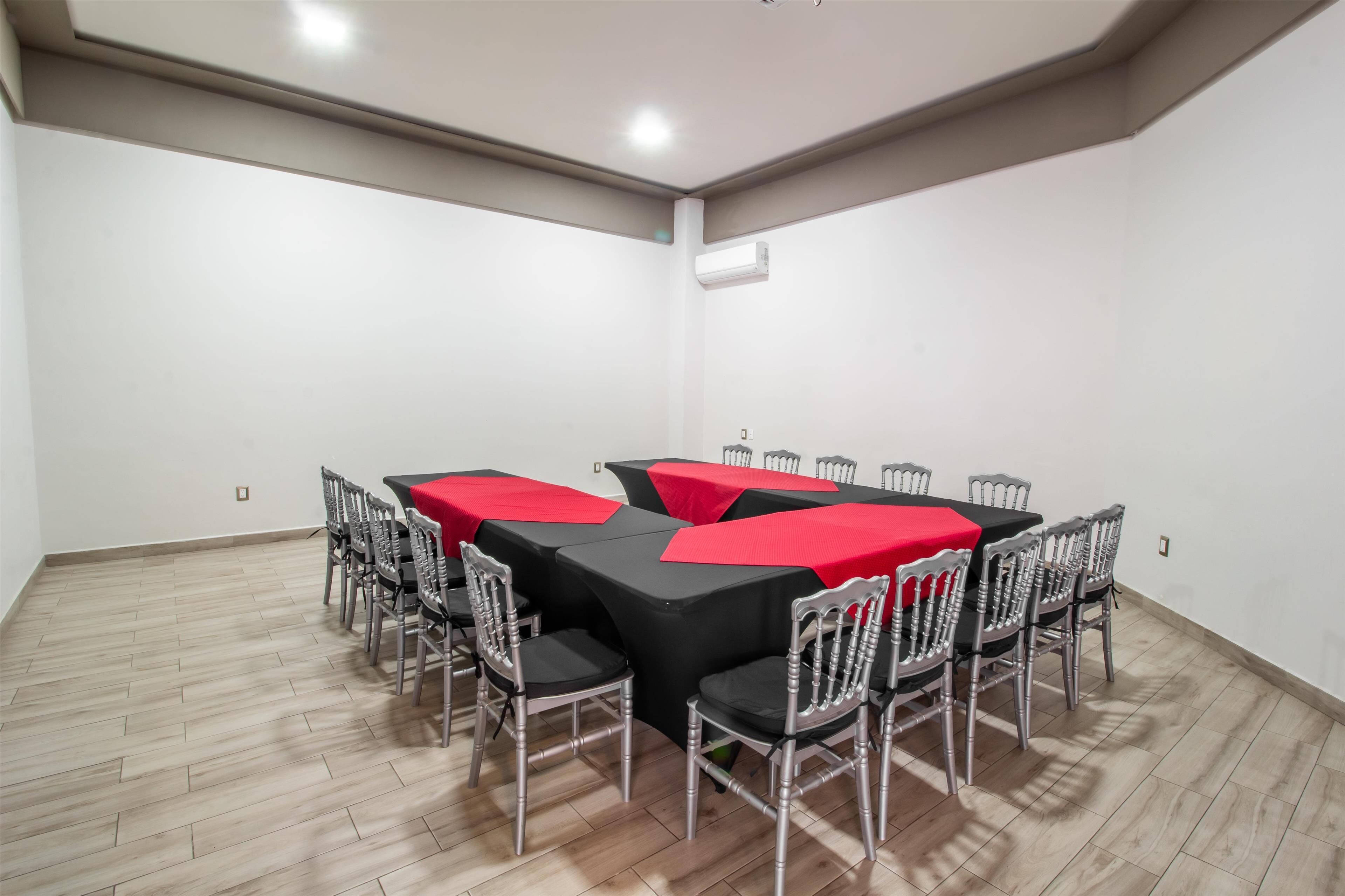 A conference room with a black table and red tablecloths, surrounded by metal chairs.
