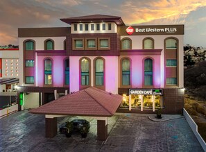 A hotel with a sign reading "Best Western PLUS" and a "Garden Café" sign below.