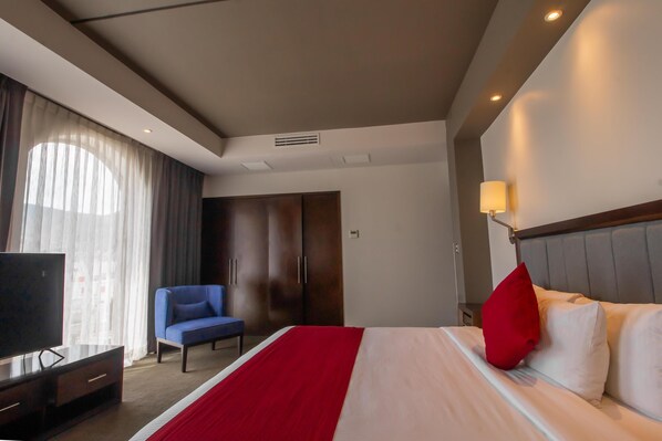 Une chambre d’hôtel équipée d’un lit, d’une télévision, d’un bureau, d’une chaise et d’une armoire.