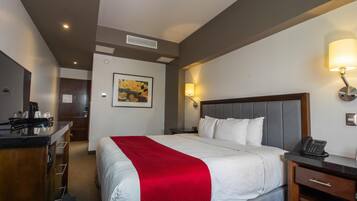 Habitación de hotel con cama, mesita de noche, lámpara y un cuadro en la pared.