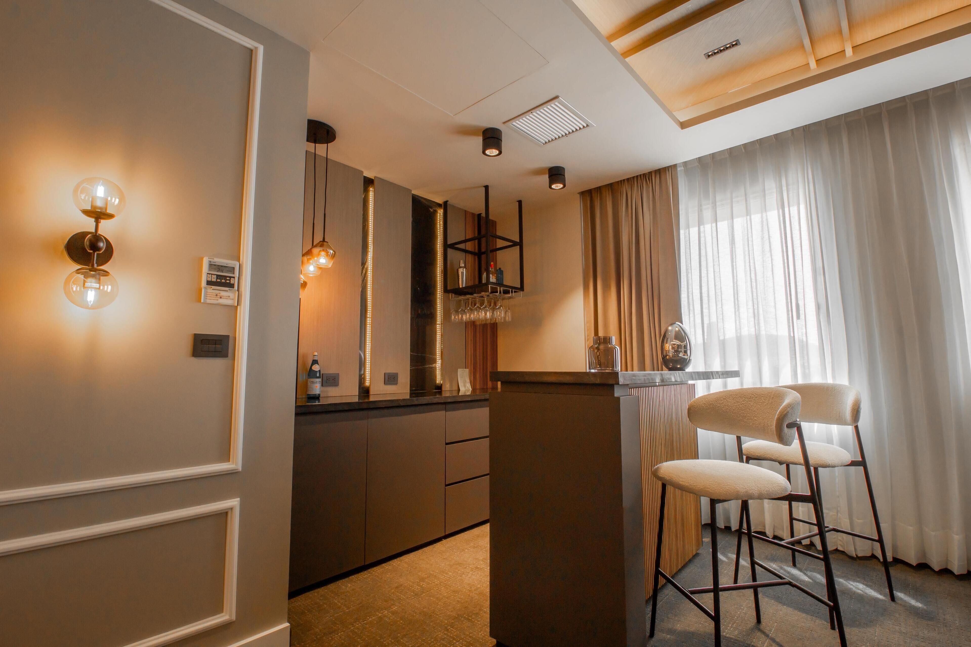 A modern kitchen with a bar area, bar stools, and a wine rack.