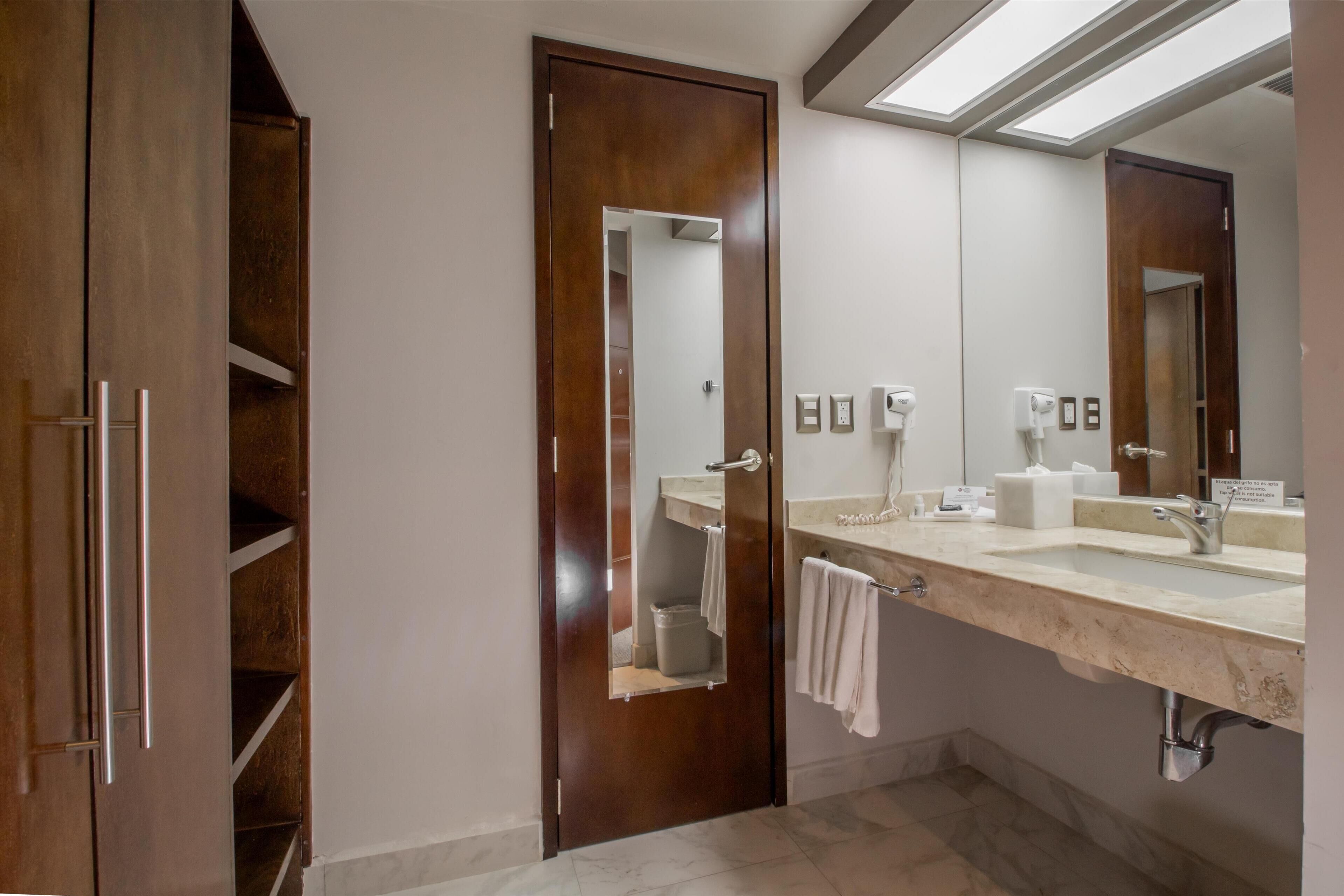 A modern bathroom with a large mirror, a sink, and a towel rack.