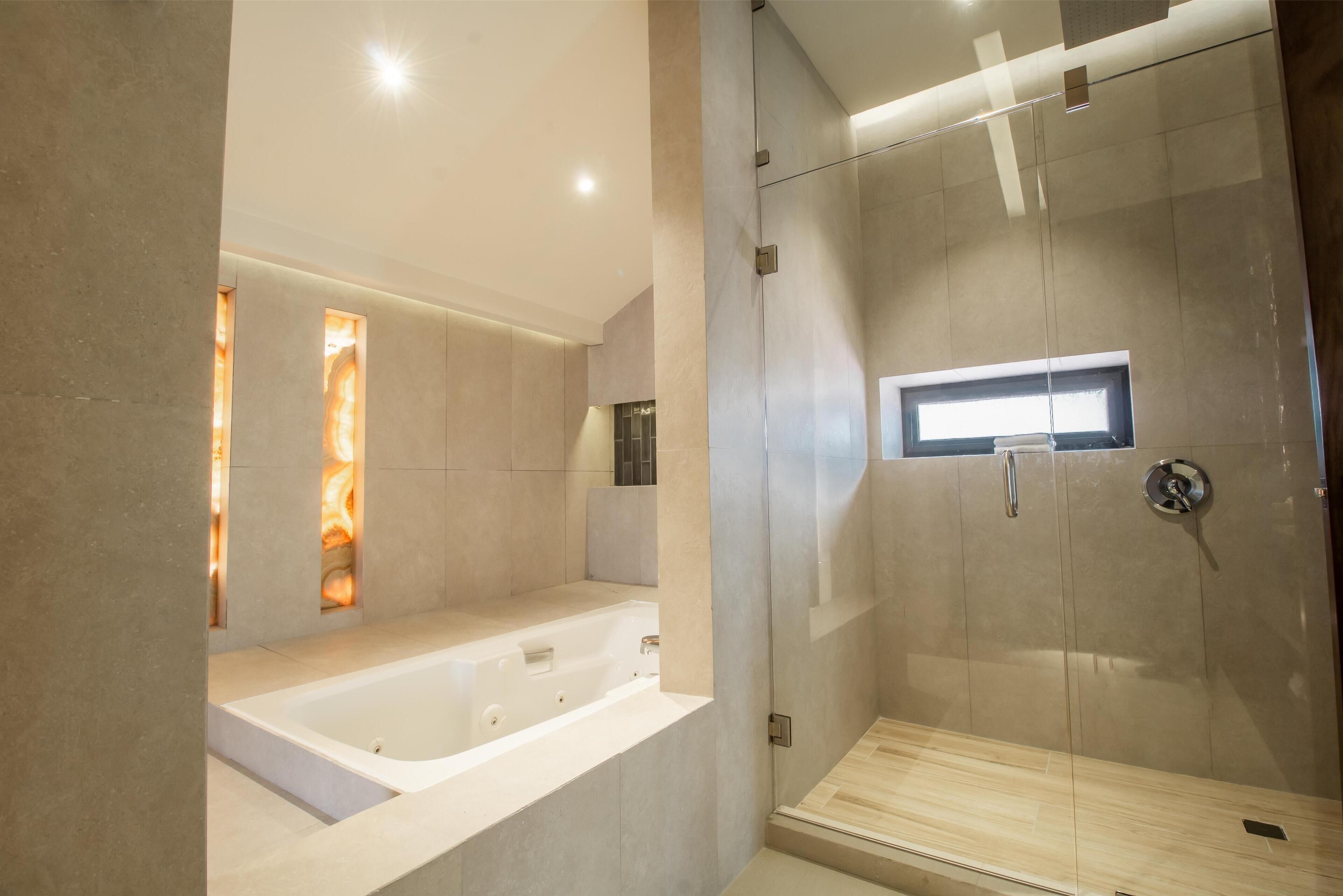 Une salle de bain moderne avec une baignoire, une douche à parois de verre et une petite fenêtre.