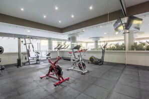A modern gym with various exercise equipment, large windows, and a clean, spacious layout.