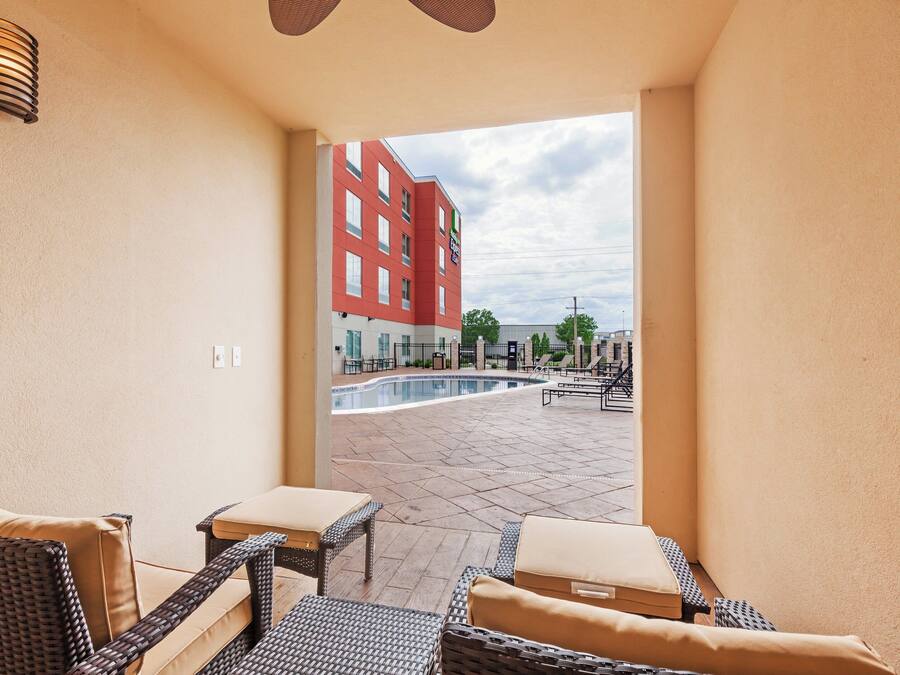 Ett hotellrum med utsikt över en utomhuspool och en röd byggnad i bakgrunden.