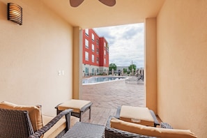 Une chambre d’hôtel avec vue sur une piscine extérieure et un bâtiment rouge en arrière-plan.