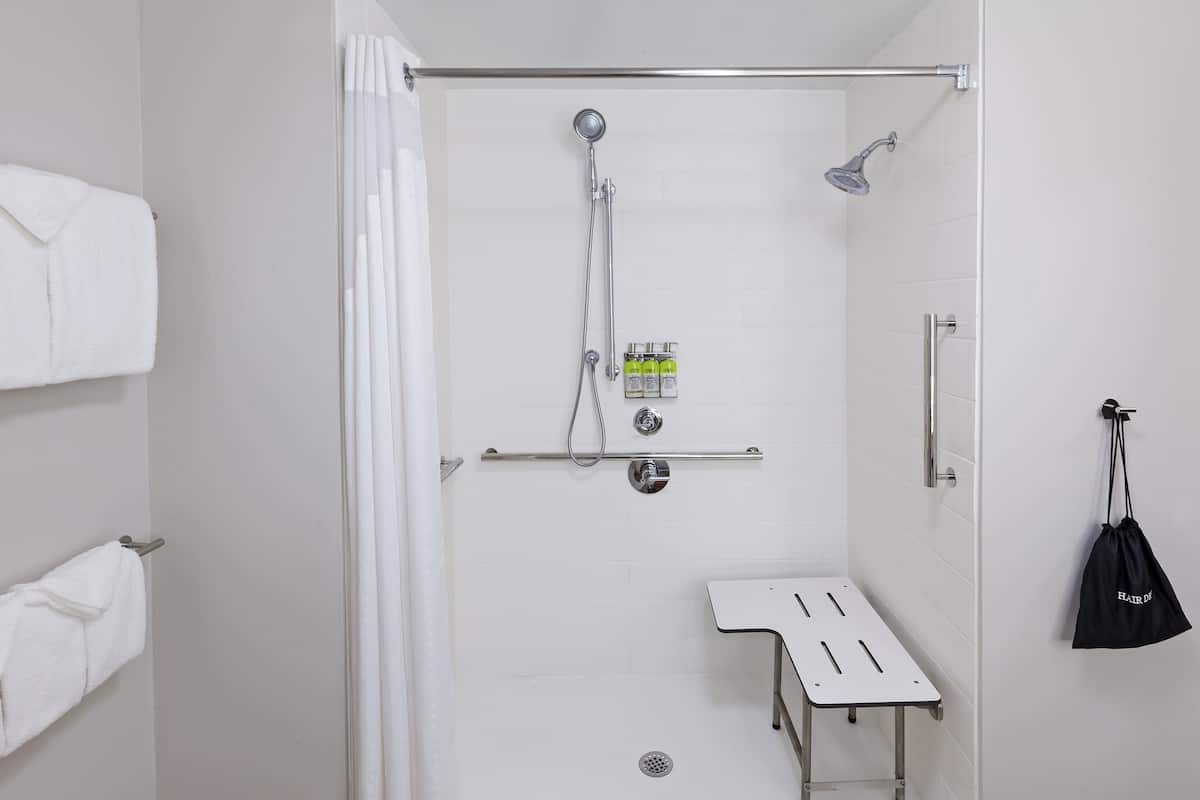 Un espace douche équipé d’une barre d’appui, d’un porte-serviettes et d’une petite table.
