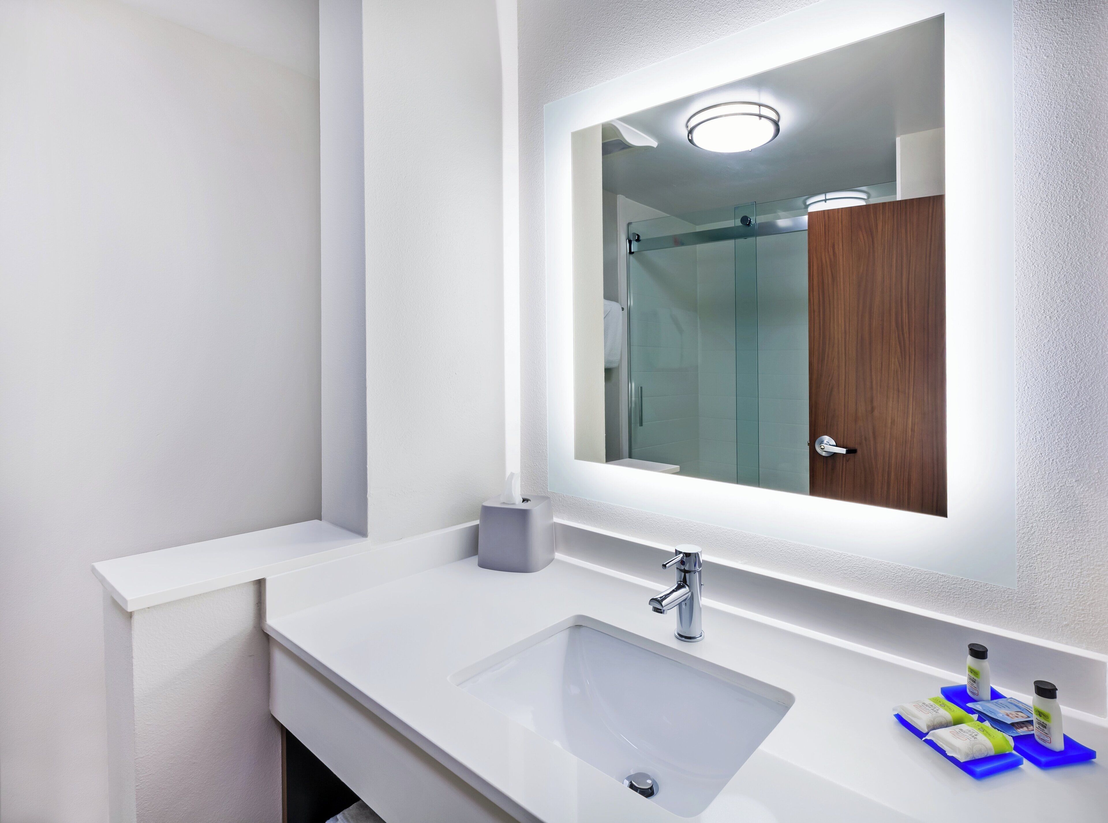 Un baño moderno con un lavabo blanco, un espejo y cabina de ducha de vidrio.