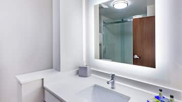 Un baño moderno con un lavabo blanco, un espejo y cabina de ducha de vidrio.